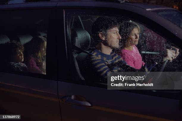 family in car at night - rain couple stockfoto's en -beelden