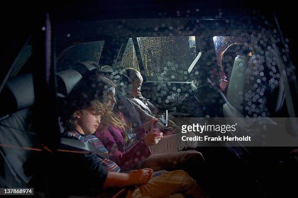family in car at night - family in rain stockfoto's en -beelden