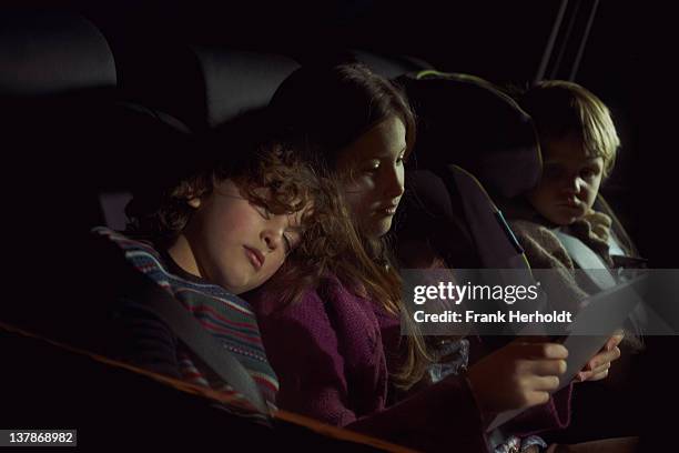 chidren in rear seat of car - girl in car with ipad stock-fotos und bilder