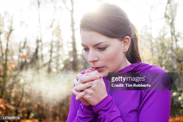 woman warming hands on cold day. - freddo foto e immagini stock