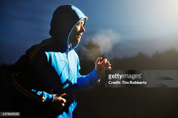 male athlete running at night with mp3 player. - winter sport stock-fotos und bilder