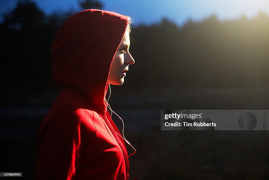 Young woman in hooded top listening to music.