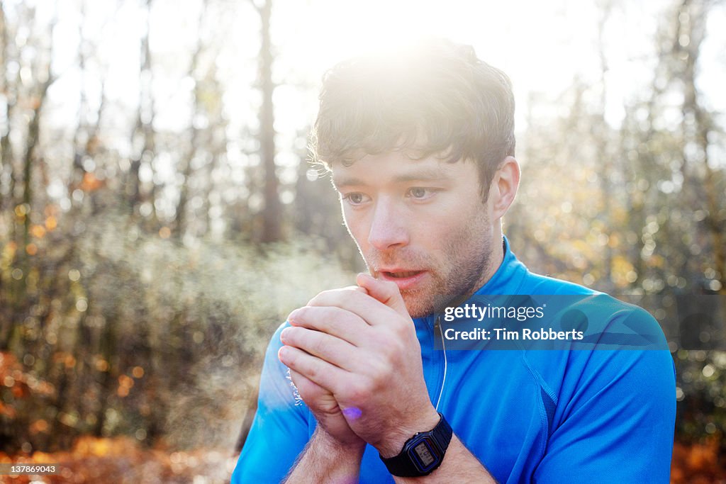 Young man breathing on hands for warmth.