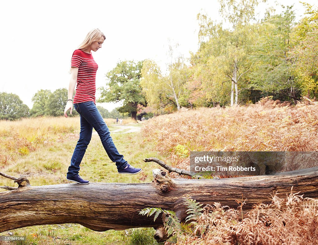 Young woman walking on log.