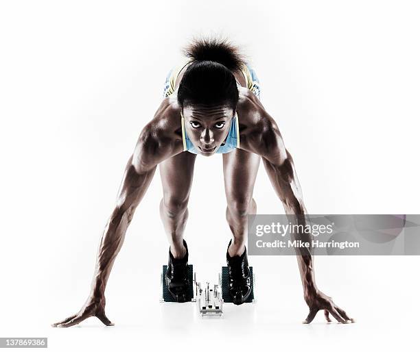 athletic female sprinter on starting blocks - starting block stockfoto's en -beelden