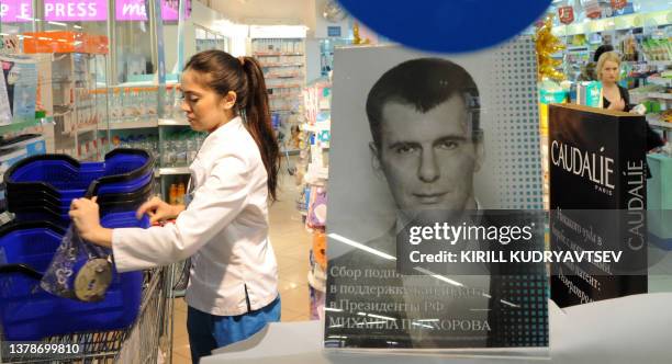 Women walk inside a drugstore in a Moscow department store, on January 10 with a stand with a photo of billionaire Mikhail Prokhorov, a site to...