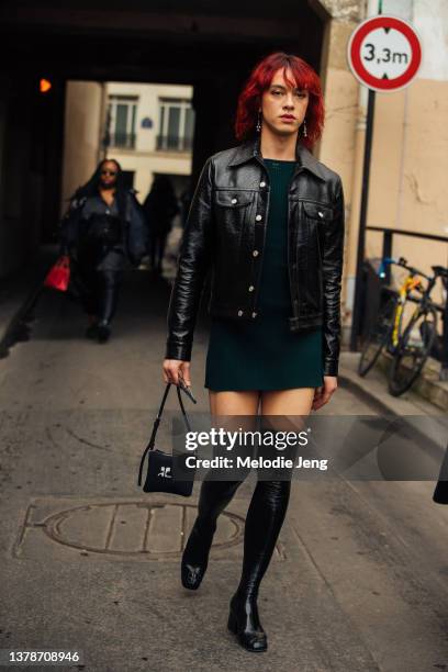 Guest wears a black leather jacket, green mini dress, thigh-high black tights leather boots, small black Courreges purse at the Courreges show at...