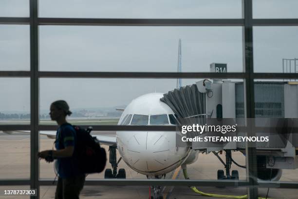 Traveler walks past a United Airlines aircraft, ahead of the July 4th holiday, at Ronald Reagan Washington National Airport in Arlington, Virginia,...