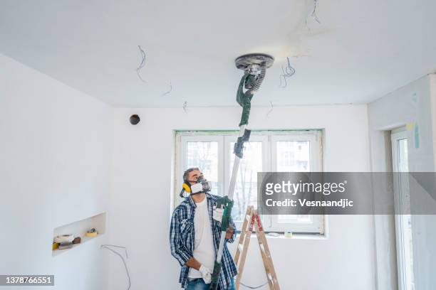 man using vacuum sanding machine on ceiling and walls - flat renovation stock pictures, royalty-free photos & images