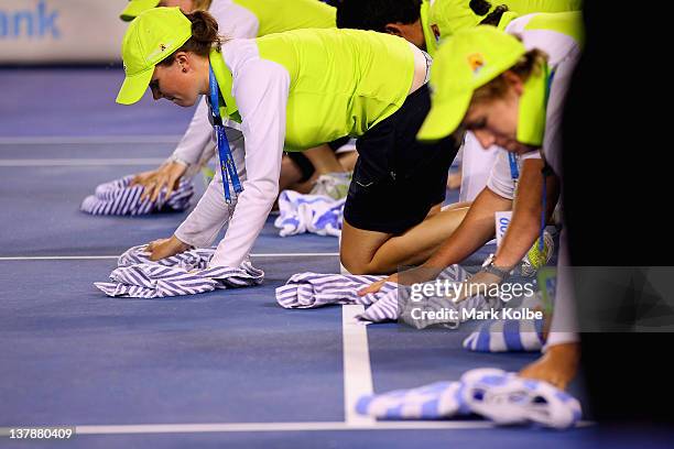 Officials wipe the rain off the main court with towels during a break in play for rain in the men's final match between Rafael Nadal of Spain and...