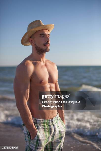 portrait of handsome man at the beach - bauchmuskel stock-fotos und bilder