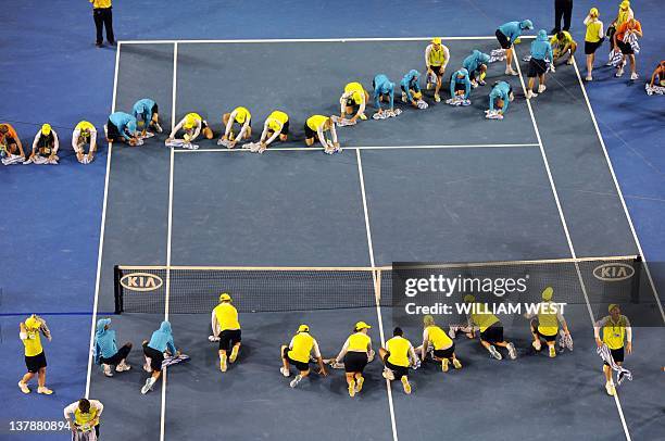 Assistants clean the court during a rain delay as Novak Djokovic of Serbia plays against Rafael Nadal of Spain in the men's final match on day 14 of...