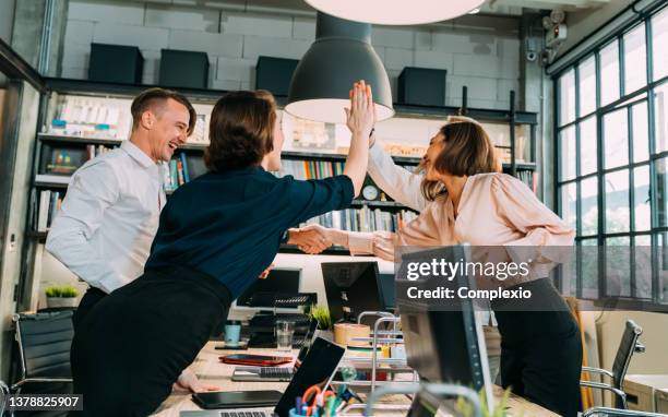 gruppe von geschäftsleuten, die high-five geben - immobilienbüro stock-fotos und bilder