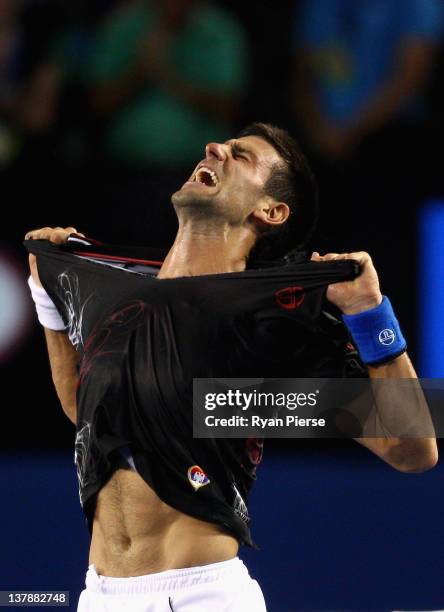 Novak Djokovic of Serbia rips his shirt off after winning championship point in his men's final match against Rafael Nadal of Spain during day...