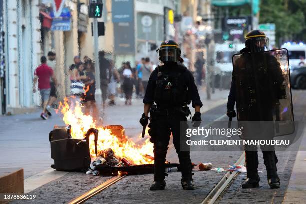 French riot police officers stand guard next to a burnt out trash bin during a demonstration against police in Marseille, southern France on July 1...