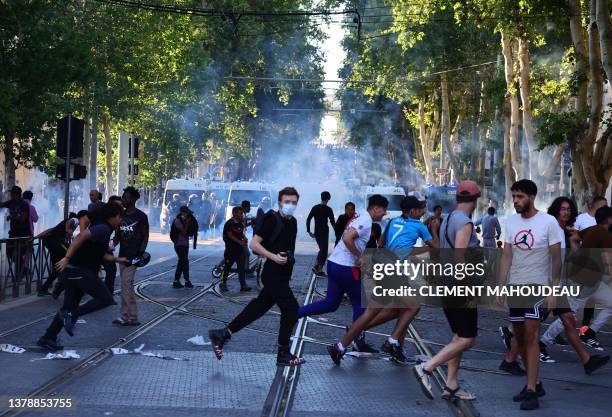 Protesters run from launched tear gas canisters during clashes with police in Marseille, southern France on July 1 after a fourth consecutive night...