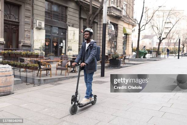 giovane afroamericano che si diverte per la città, in sella al suo scooter a spinta - motorized vehicle riding foto e immagini stock