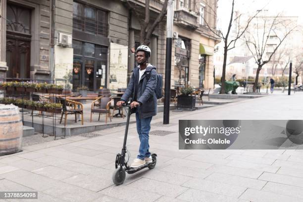 african american young man enjoying through the city, riding his push scooter - 選區選民 個照片及圖片檔