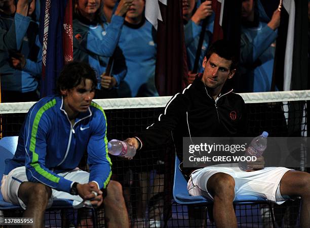 Novak Djokovic of Serbia offers water to Rafael Nadal of Spain after victory in their men's singles final match on the twelfth day of the Australian...