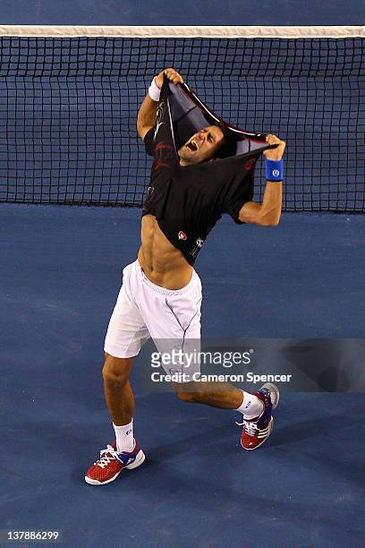 Novak Djokovic of Serbia rips his shirt off after winning championship point in his men's final match against Rafael Nadal of Spain during day...