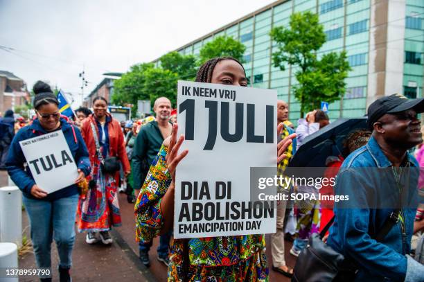 Black woman is seen holding a placard against slavery as they take part in the Keti Koti parade. Keti Koti marks the date when slavery was abolished...