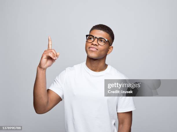 cheerful young man pointing at copy space - smirk stock pictures, royalty-free photos & images