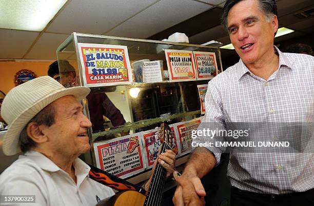 Republican presidential hopeful Mitt Romney greets musician as he meets with voters at Casa Marin restaurant in Hialeah, Florida, January 29, 2012....