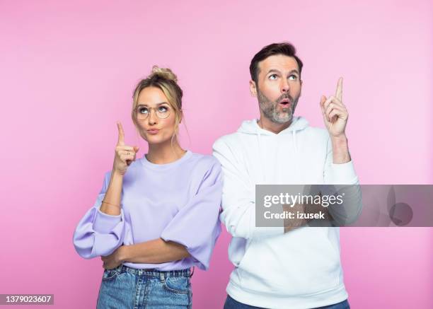 mid adult couple pointing while looking up - couple pointing imagens e fotografias de stock