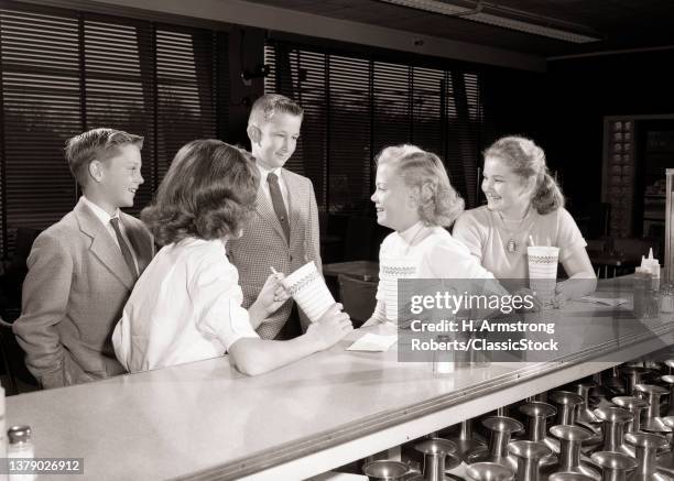 1950s Two Boys And Three Girls Teenagers Together At Soda Fountain Counter Talking Flirting Drinking Milk Shakes.