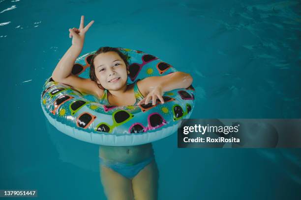 girl smiling looking at the camera with an inflatable in the water of a pool - tube girl fotografías e imágenes de stock