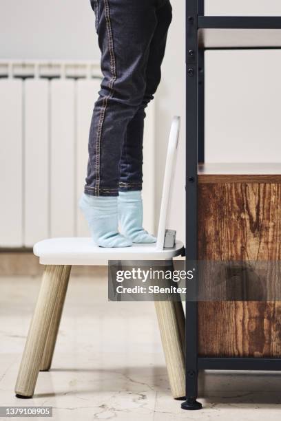 little girl on tiptoe on a chair - zu klein stock-fotos und bilder