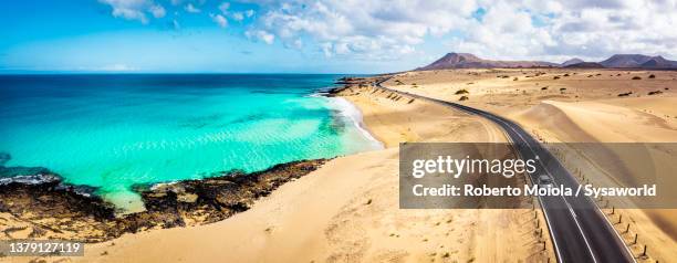 car traveling on desert road beside the ocean - fuerteventura stock-fotos und bilder