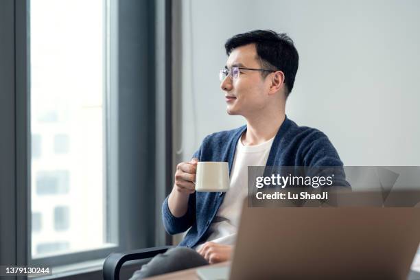 business people sit in the office and look out of the window at tea time - man resting stock pictures, royalty-free photos & images