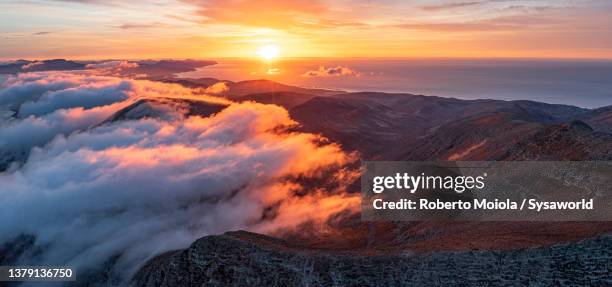 mountains emerging from clouds at dawn, fuerteventura - sonnenuntergang sonnenaufgang landschaft stock-fotos und bilder