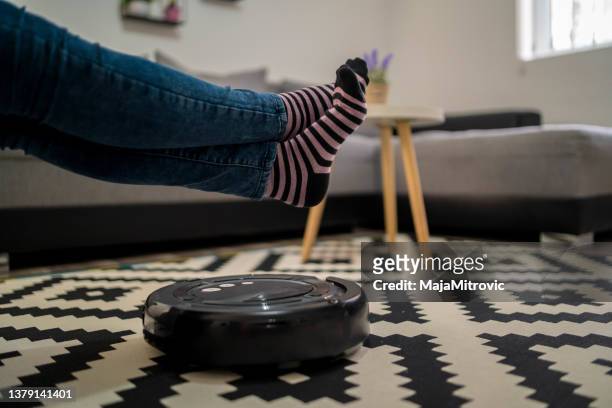 robotic vacuum cleaner cleaning the room while woman resting on sofa, closeup - robot vacuum stock pictures, royalty-free photos & images
