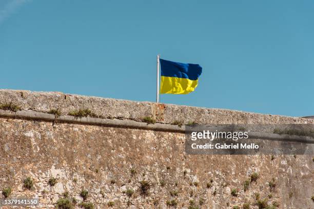 ukrainian flag flying over the wall against blue sky - ukraine war stock pictures, royalty-free photos & images
