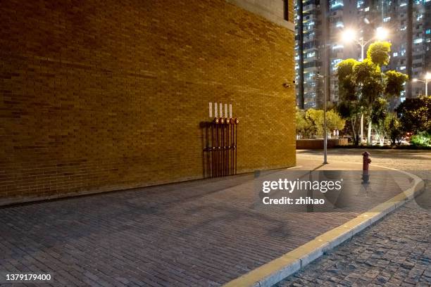 night view of side road outside city brick wall building - corners stock-fotos und bilder