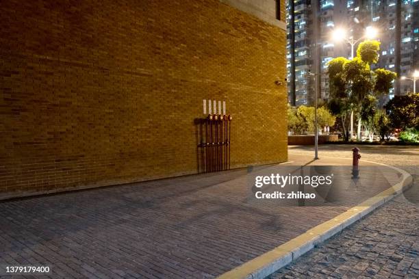 night view of side road outside city brick wall building - sidewalk stockfoto's en -beelden