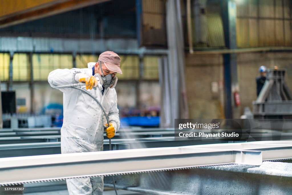 Man painting metal in factory