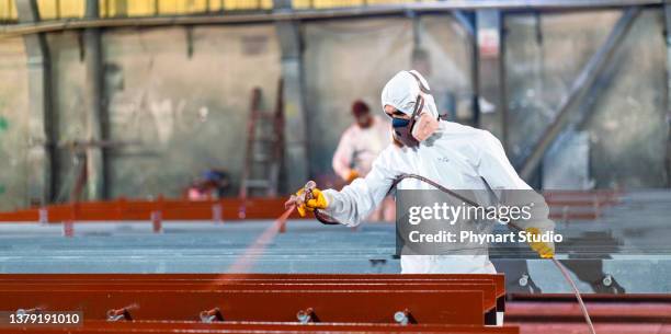 hombre pintando metal en fábrica - pintura con pistola fotografías e imágenes de stock