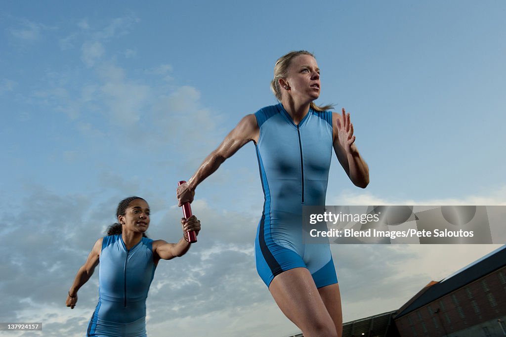 Runners passing baton in relay race