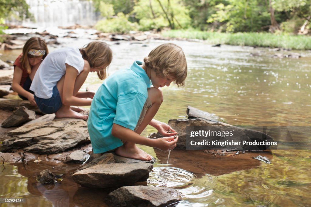 Caucasian children squatting near stream