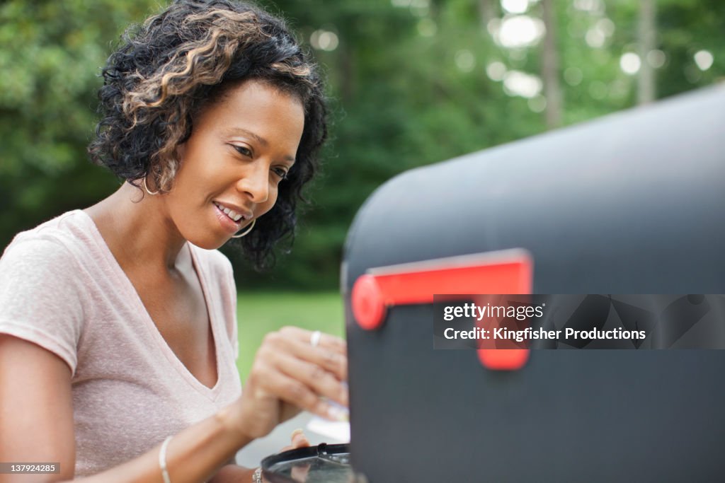 African American woman taking mail from mailbox