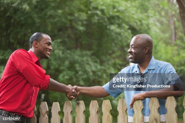 african american nachbarn grüßen einander auf zaun - nachbarn stock-fotos und bilder