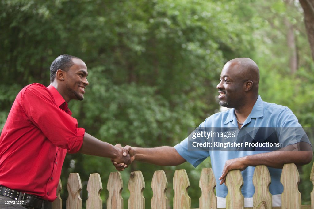 African American neighbors greeting each other over fence