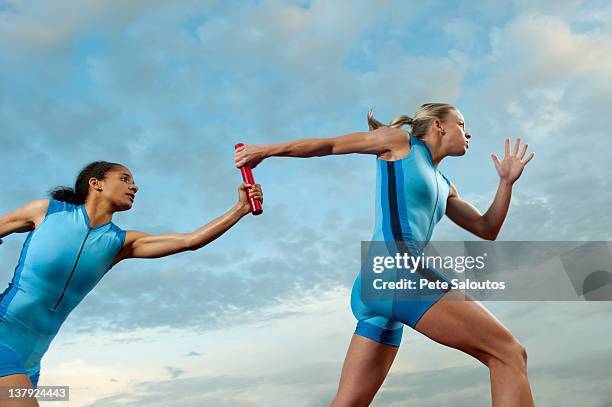 runners passing baton in relay race - track and field baton stock pictures, royalty-free photos & images