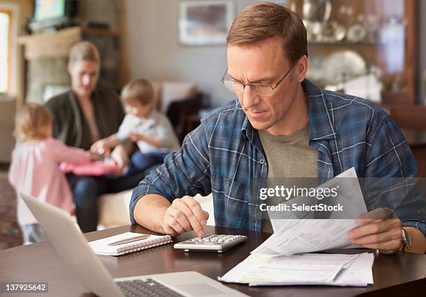 father paying bills with family behind him - day in the life usa stockfoto's en -beelden