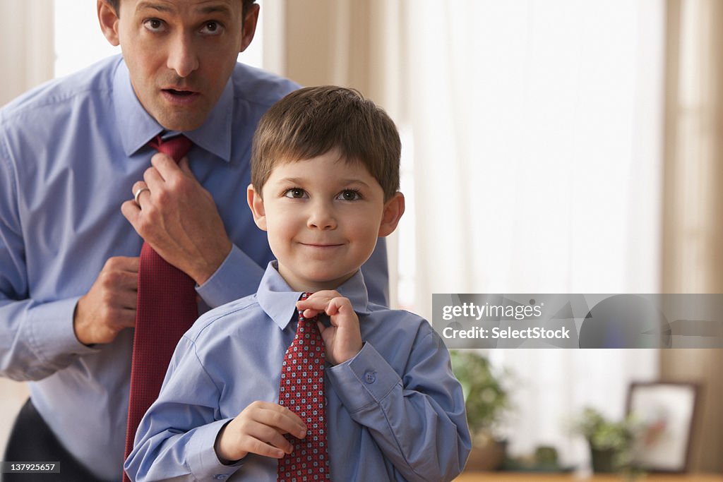 Father and son fixing ties together