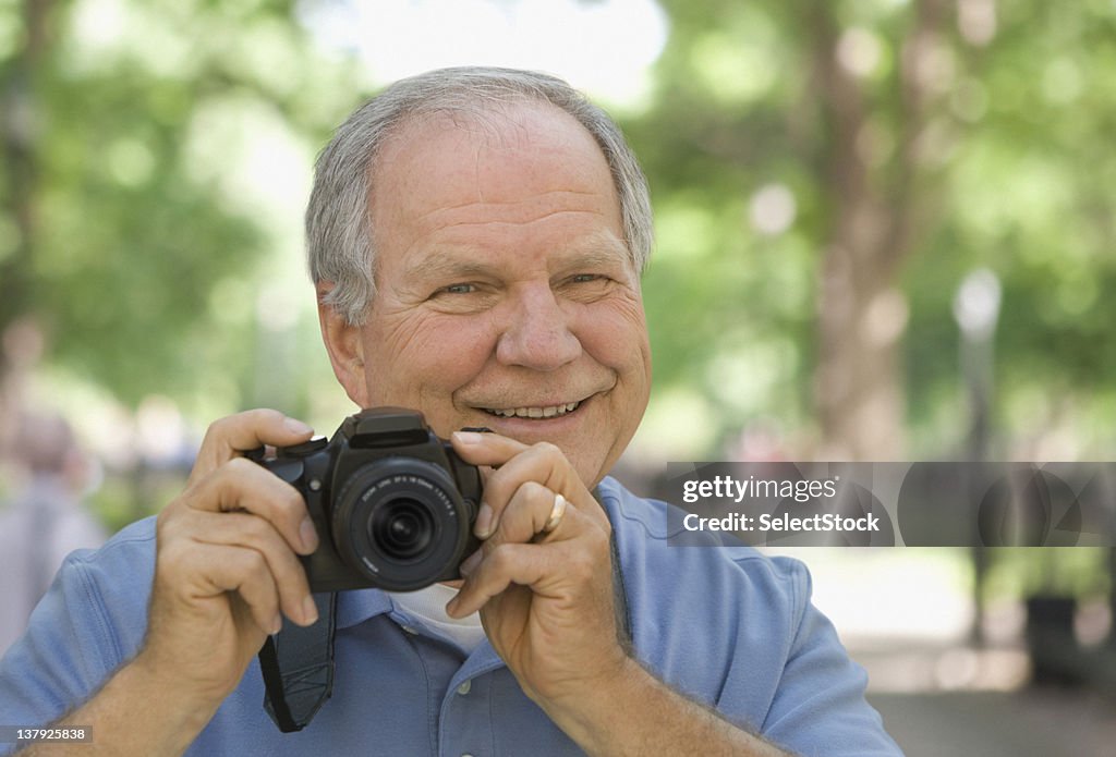 Elderly man taking photograph with camera
