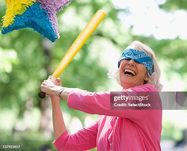 idosos mulher tentando acertar um pinhata - pinhata imagens e fotografias de stock